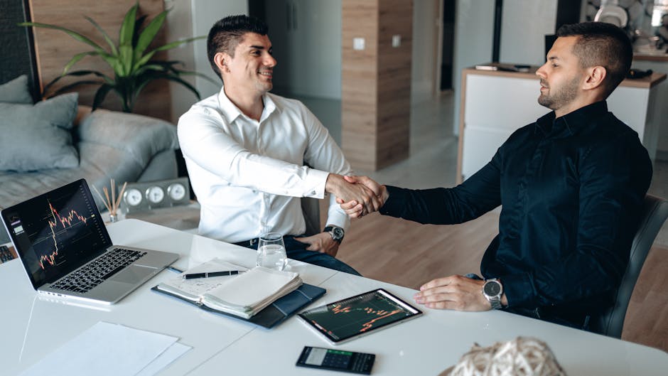 Two businessmen shaking hands in an office, symbolizing a successful business agreement.
